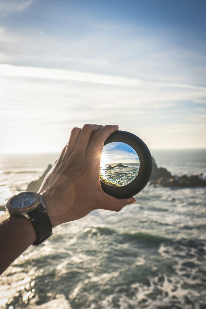 A hand holding a monocular to the horizon.